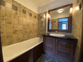 This charming bathroom features a spacious bathtub with a grab bar, perfect for a relaxing soak.