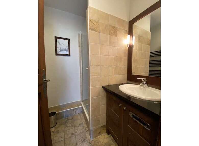 This bathroom features a spacious walk-in shower with tiled walls and a modern vanity with a sleek countertop and ample storage.