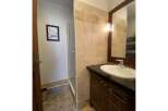 This bathroom features a spacious walk-in shower with tiled walls and a modern vanity with a sleek countertop and ample storage.