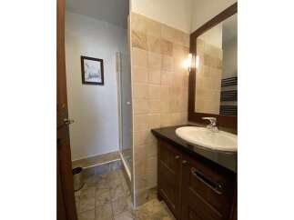 This bathroom features a spacious walk-in shower with tiled walls and a modern vanity with a sleek countertop and ample storage.