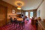 Experience cozy living in this charming mountain retreat, featuring a warm wood-paneled dining area with a rustic chandelier and comfortable seating.