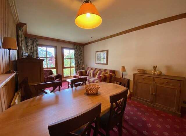 Experience comfortable living in this inviting dining and living area, featuring a spacious wooden dining table perfect for family meals.