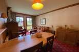 Experience comfortable living in this inviting dining and living area, featuring a spacious wooden dining table perfect for family meals.