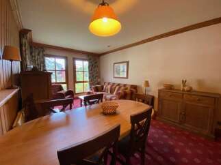 Experience comfortable living in this inviting dining and living area, featuring a spacious wooden dining table perfect for family meals.