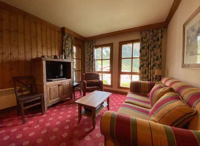 Experience cozy living in this charming room featuring a rustic wooden entertainment center with a television and ample storage.