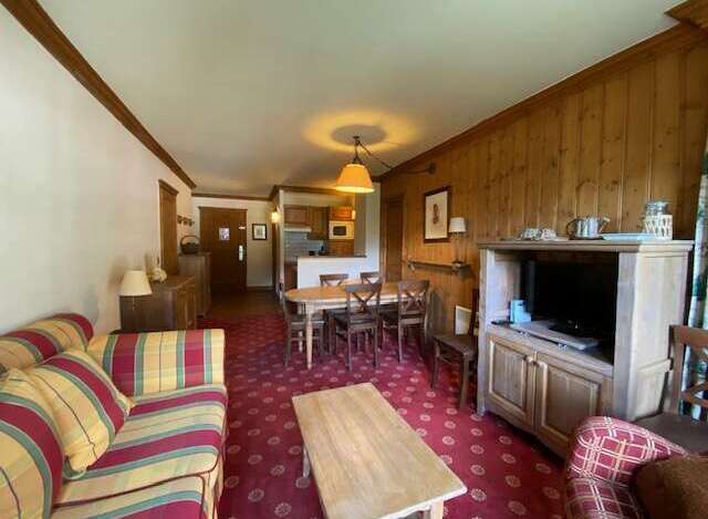 Experience cozy living in this charming apartment featuring a comfortable striped sofa and a rustic wooden dining set perfect for family meals.