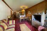 Experience cozy living in this charming apartment featuring a comfortable striped sofa and a rustic wooden dining set perfect for family meals.