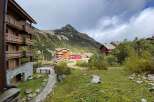 Experience mountain living in this charming alpine village setting, featuring traditional wooden chalets nestled against a backdrop of majestic peaks.