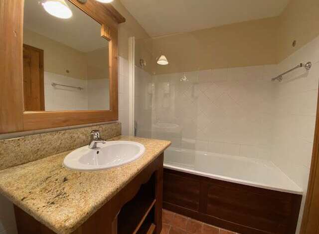 This charming bathroom features a spacious bathtub with a glass enclosure, perfect for relaxing soaks.