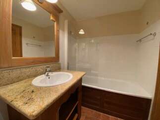 This charming bathroom features a spacious bathtub with a glass enclosure, perfect for relaxing soaks.