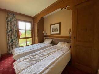 Experience comfort and style in this charming bedroom featuring two inviting beds, perfect for families or groups.