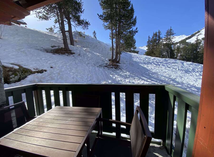 Enjoy breathtaking mountain views from this charming balcony, complete with a rustic wooden table and chairs.