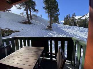 Enjoy breathtaking mountain views from this charming balcony, complete with a rustic wooden table and chairs.