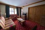 Experience cozy living in this charming room featuring a vibrant, patterned carpet and comfortable seating options.