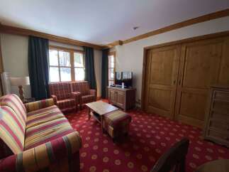 Experience cozy living in this charming room featuring a vibrant, patterned carpet and comfortable seating options.