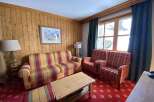 Experience cozy mountain living in this charming room featuring warm wood paneling and a vibrant plaid sofa and armchairs.