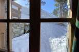 Experience breathtaking mountain views from this cozy cabin, featuring large windows that showcase a pristine snowy landscape.