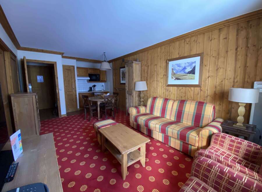 Experience cozy living in this charming apartment featuring a vibrant living area with a plaid sofa and accent chairs, perfect for relaxation.