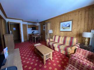 Experience cozy living in this charming apartment featuring a vibrant living area with a plaid sofa and accent chairs, perfect for relaxation.