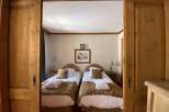 Experience alpine charm in this cozy bedroom featuring two inviting twin beds, each adorned with plush brown throws and crisp white linens.