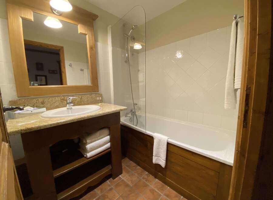 This charming bathroom features a spacious bathtub with a glass shower screen, perfect for relaxing after a long day.