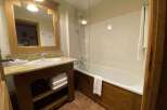 This charming bathroom features a spacious bathtub with a glass shower screen, perfect for relaxing after a long day.