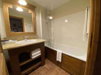 This charming bathroom features a spacious bathtub with a glass shower screen, perfect for relaxing after a long day.