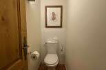 This charming powder room features a classic white toilet, complemented by a decorative framed artwork of a woodland creature above the tiled backsplash.