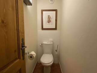 This charming powder room features a classic white toilet, complemented by a decorative framed artwork of a woodland creature above the tiled backsplash.