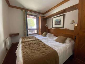 Experience cozy mountain living in this charming bedroom featuring two comfortable beds adorned with plush brown throws and accent pillows.