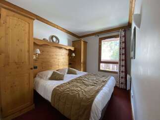 Experience cozy mountain living in this charming bedroom featuring a spacious wooden headboard and a comfortable queen-sized bed adorned with plush pillows and a warm, quilted throw.