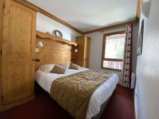Experience cozy mountain living in this charming bedroom featuring a comfortable queen-sized bed adorned with plush pillows and a warm, quilted throw.