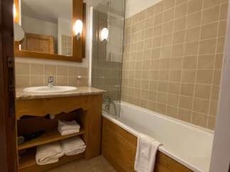 This charming bathroom features a spacious bathtub with a glass shower screen, perfect for relaxing after a long day.