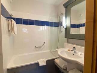 This charming bathroom features a pristine white bathtub with a convenient grab bar and a sleek showerhead.