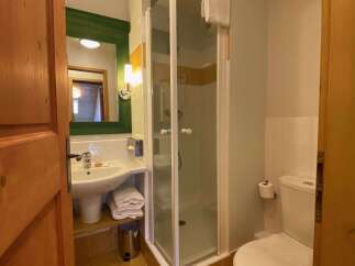 This charming bathroom features a modern sink with a green-framed mirror and a convenient shower stall.