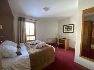 Experience comfort and convenience in this well-appointed hotel room, featuring a plush bed adorned with crisp white linens and two neatly folded bathrobes.