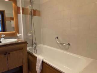This charming bathroom features a spacious bathtub with a glass shower screen, perfect for relaxing after a long day.