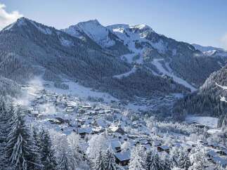 Discover a charming alpine village nestled amidst snow-covered mountains and dense pine forests.
