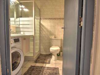 This bathroom features a convenient washing machine and a separate shower enclosure, perfect for modern living.