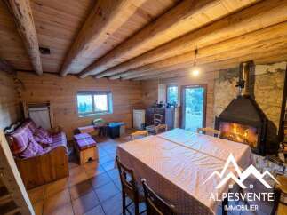 Experience cozy living in this charming log cabin featuring a rustic stone fireplace, perfect for warming up after a day in the mountains.