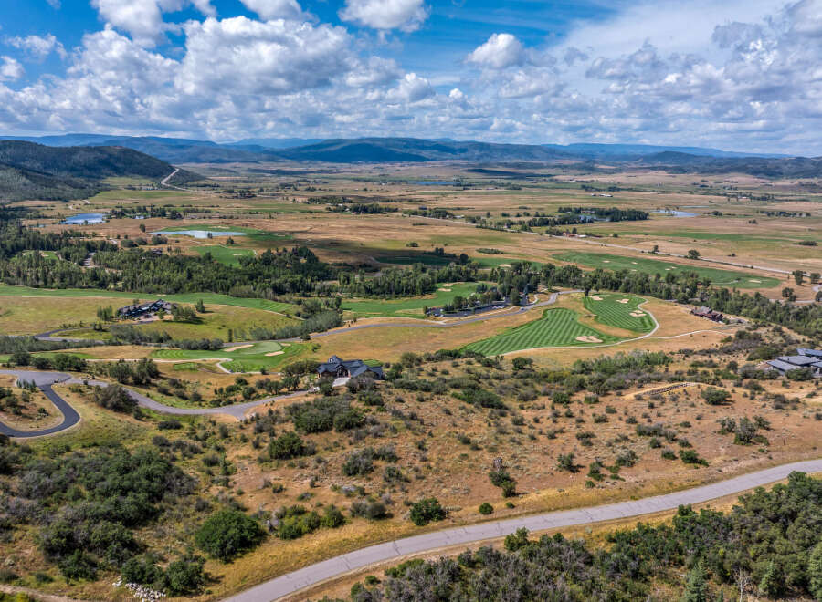 Experience luxury living with this stunning aerial view of a sprawling estate nestled amidst rolling hills and a pristine golf course.