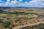 Experience luxury living with this stunning aerial view of a sprawling estate nestled amidst rolling hills and a pristine golf course.