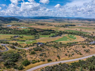 Experience luxury living with this stunning aerial view of a sprawling estate nestled amidst rolling hills and a pristine golf course.