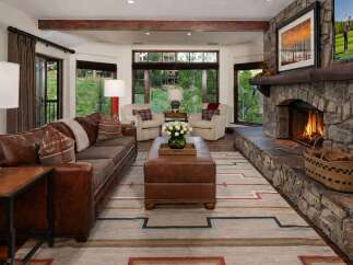 Experience rustic luxury in this inviting living room, featuring a grand stone fireplace and a plush leather sofa perfect for cozy evenings.