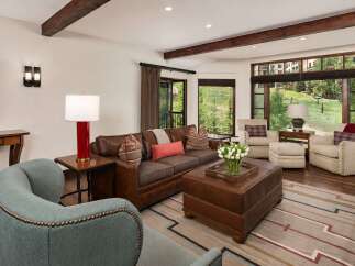 Experience luxury mountain living in this stunning living room, featuring a plush leather sofa, comfortable armchairs, and a large leather ottoman.