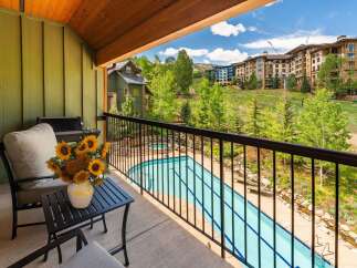 Enjoy breathtaking mountain views from this stunning balcony, complete with comfortable seating and a charming vase of sunflowers.