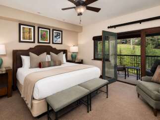 Experience luxury mountain living in this beautifully appointed bedroom, featuring a king-sized bed, plush seating, and elegant decor.
