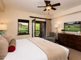 Experience luxury mountain living in this beautifully appointed bedroom, featuring a king-sized bed, a private balcony with stunning views, and a large flat-screen TV for entertainment.