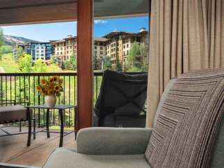 Enjoy breathtaking mountain views from this charming balcony, complete with a cozy seating area and a vase of sunflowers.