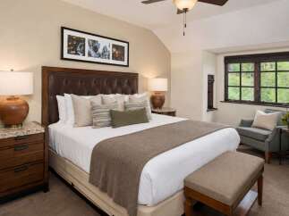 Experience luxurious comfort in this beautifully appointed bedroom, featuring a plush king-sized bed with a tufted leather headboard and elegant decorative pillows.